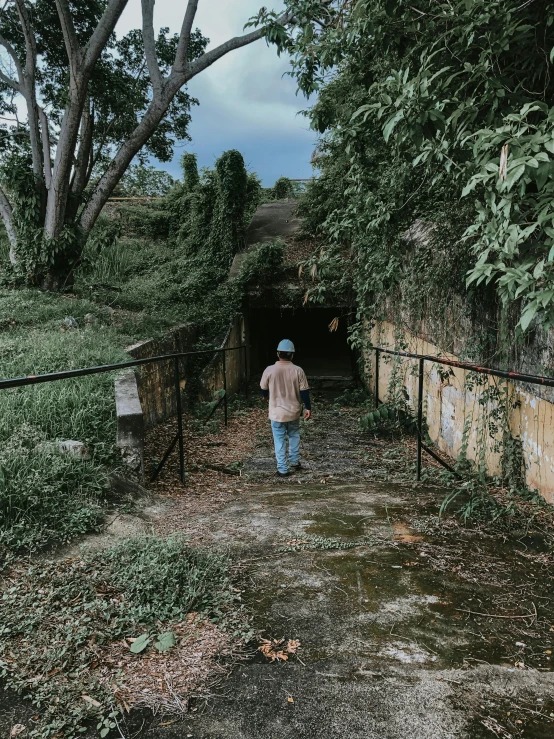 a man walking out of a tunnel into a forest, an album cover, by Lucia Peka, pexels contest winner, happening, set on singaporean aesthetic, abandoned war torn village, 😭 🤮 💕 🎀, entrance to 1900's mine