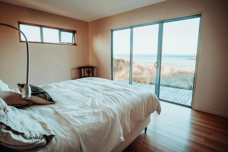 a bed sitting in a bedroom next to a window, by Liza Donnelly, unsplash, built around ocean, manuka, cheeks, evenly lit