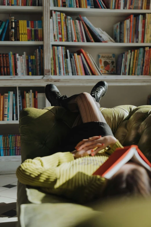 a woman laying on a couch reading a book, pexels contest winner, yellow and olive color scheme, bookshelves, sydney hanson, promo image