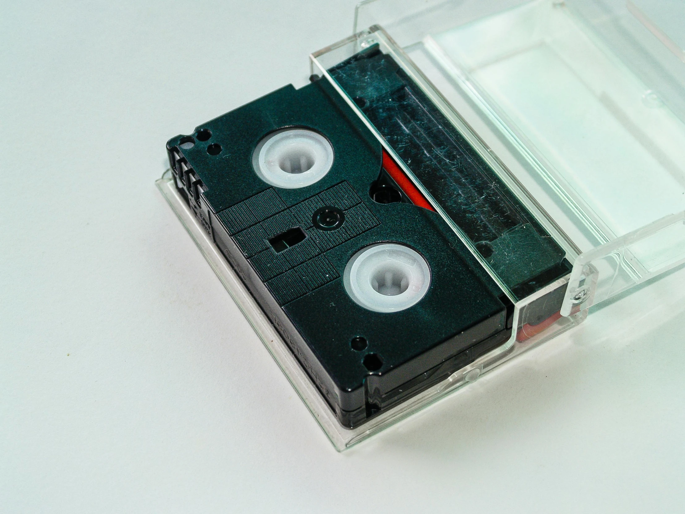 a close up of a cassette in a clear case, unsplash, video art, black 3 d cuboid device, set against a white background, old school, high quality product image”