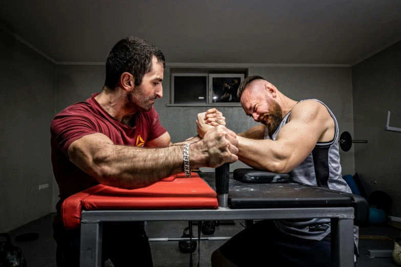 two men arm wrestling in a gym room, a photo, by Adam Marczyński, square, professional picture, battered, petros and leonid