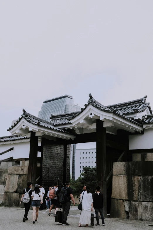 a group of people standing in front of a building, a picture, trending on unsplash, sōsaku hanga, fortress gateway, overcast gray skies, 🚿🗝📝, view from ground