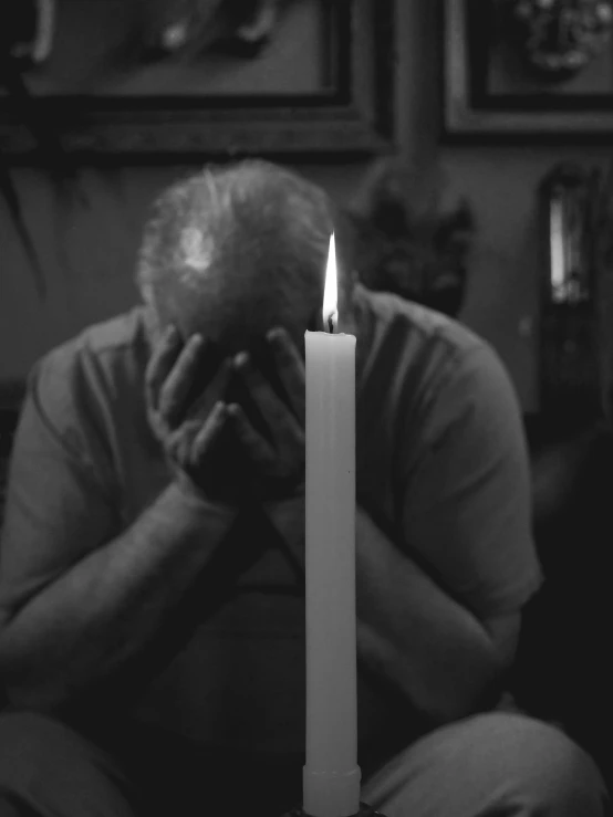 a man sitting on a couch with a candle in front of him, a black and white photo, pexels, fine art, people crying, an old man, 15081959 21121991 01012000 4k, white candles