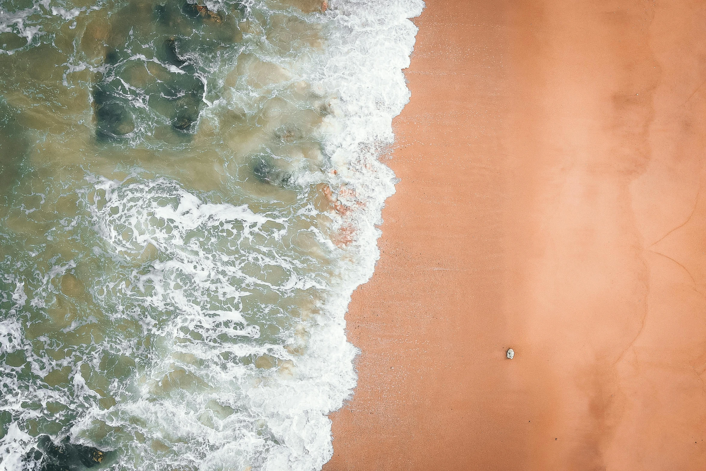 a person riding a surfboard on top of a sandy beach, inspired by Andreas Gursky, pexels contest winner, orange and white color scheme, bird view, sea foam, a single