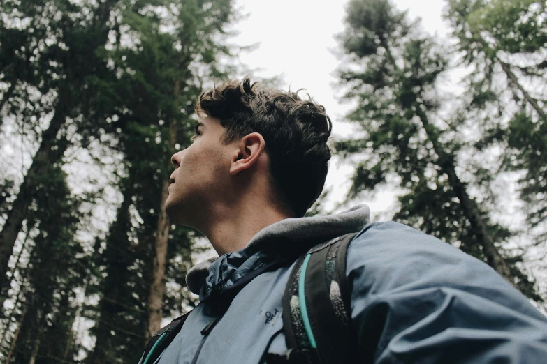 a man standing in the middle of a forest, by Carey Morris, pexels contest winner, close - up profile face, hiking clothes, looking upwards, profile image