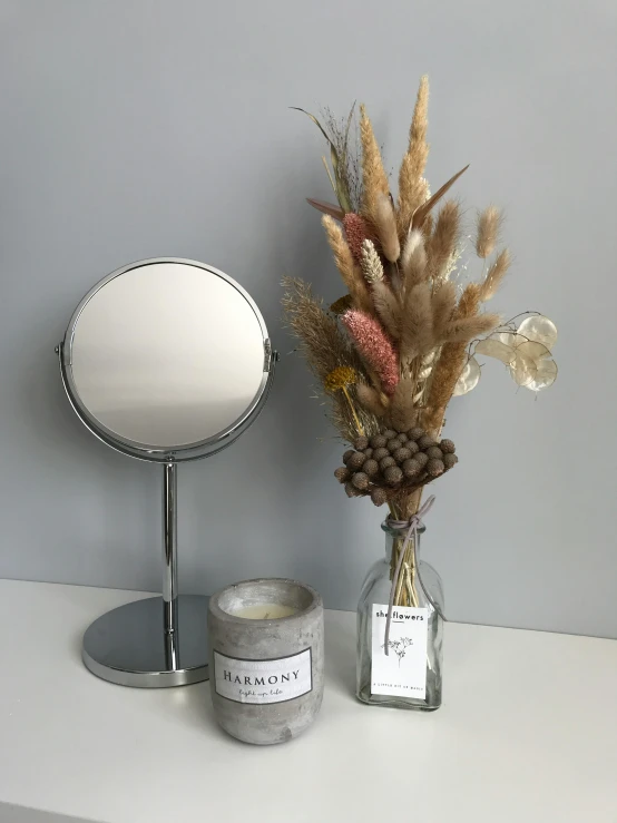 a white table topped with a mirror and a candle, a still life, by Alice Mason, instagram, dried flower, detailed product image, product view, grey and silver