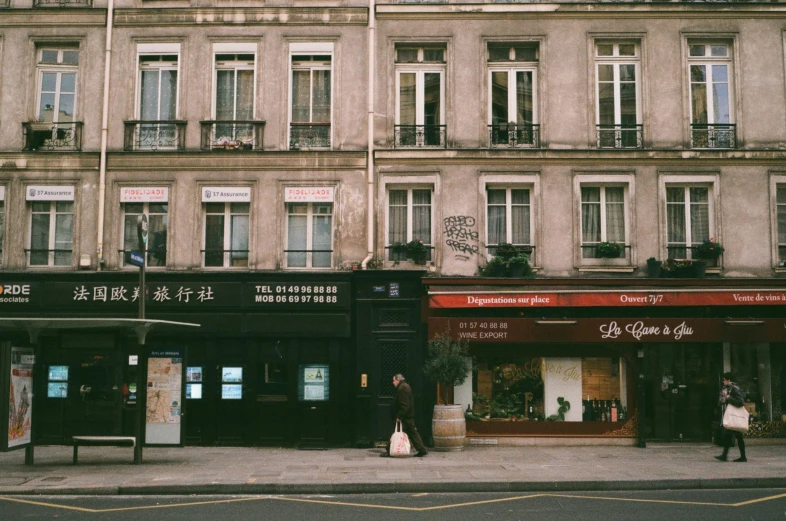 a couple of people that are standing in front of a building, a photo, unsplash, paris school, storefronts, jia ruan, 2000s photo
