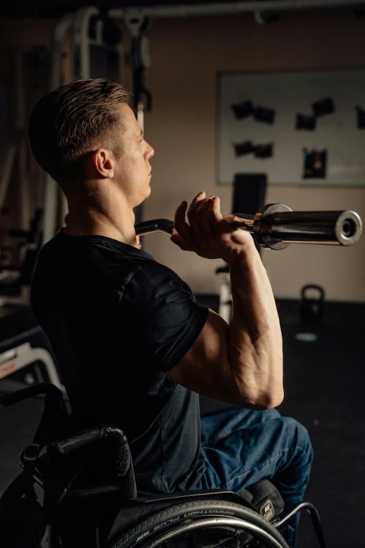 a man in a wheelchair holding a baseball bat, by Adam Marczyński, pexels contest winner, background a gym, profile image, hunched shoulders, bram sels