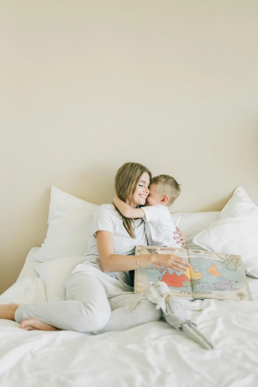 a woman sitting on top of a bed holding a baby, pexels contest winner, children's storybook, light beige pillows, profile image, boys