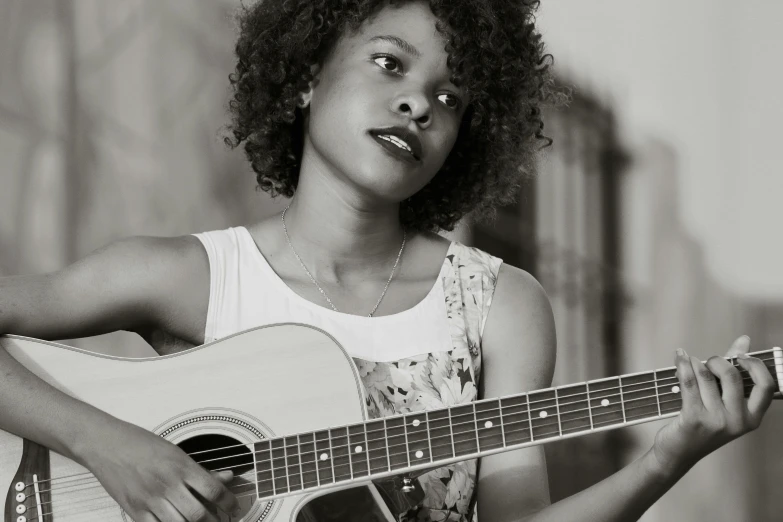 a black and white photo of a woman playing a guitar, by Ella Guru, pexels contest winner, with brown skin, black young woman, looking towards camera, afro