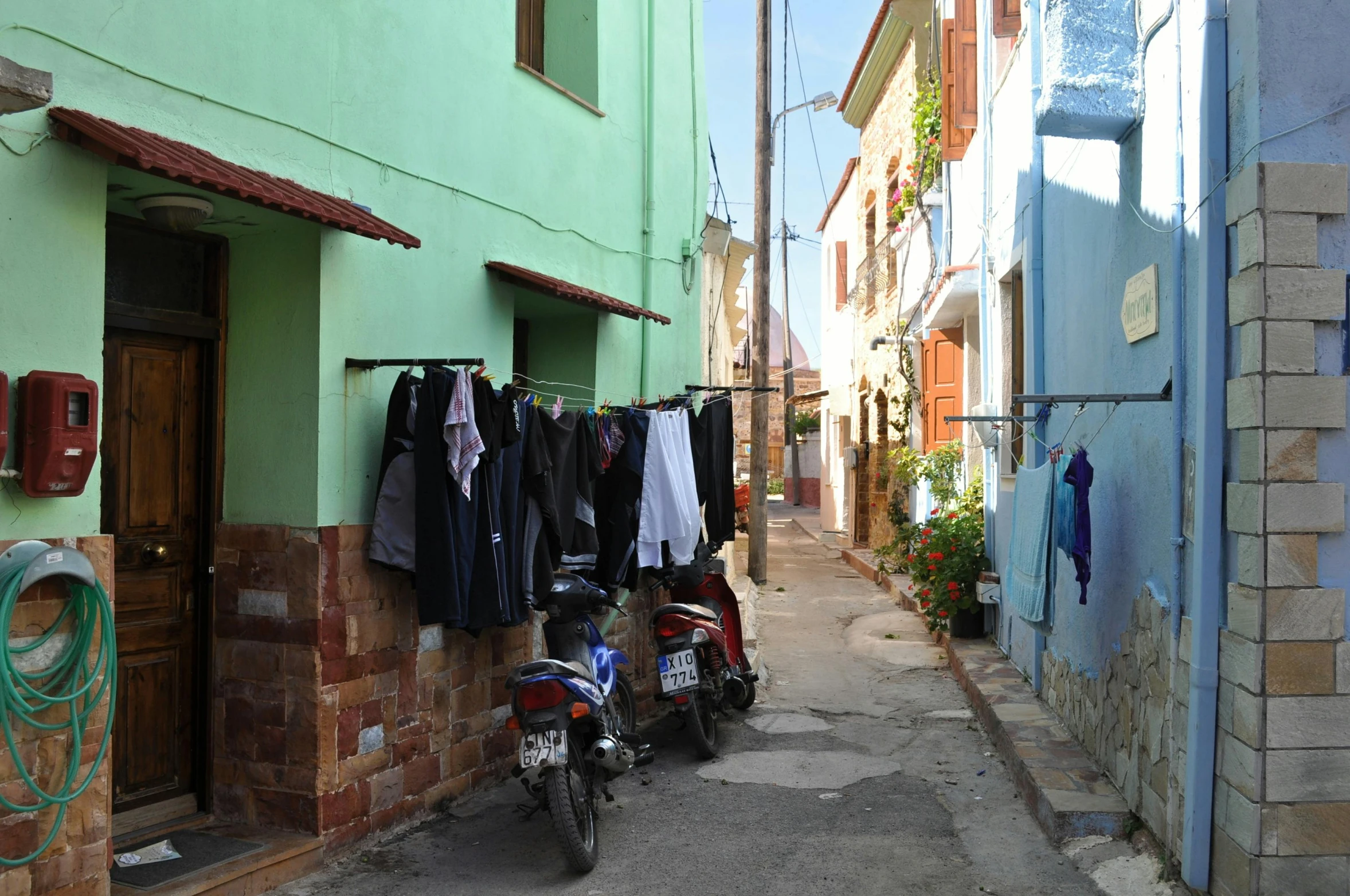 a motorcycle parked in front of a green building, by Meredith Dillman, pexels contest winner, laundry hanging, cyprus, alley, panoramic shot