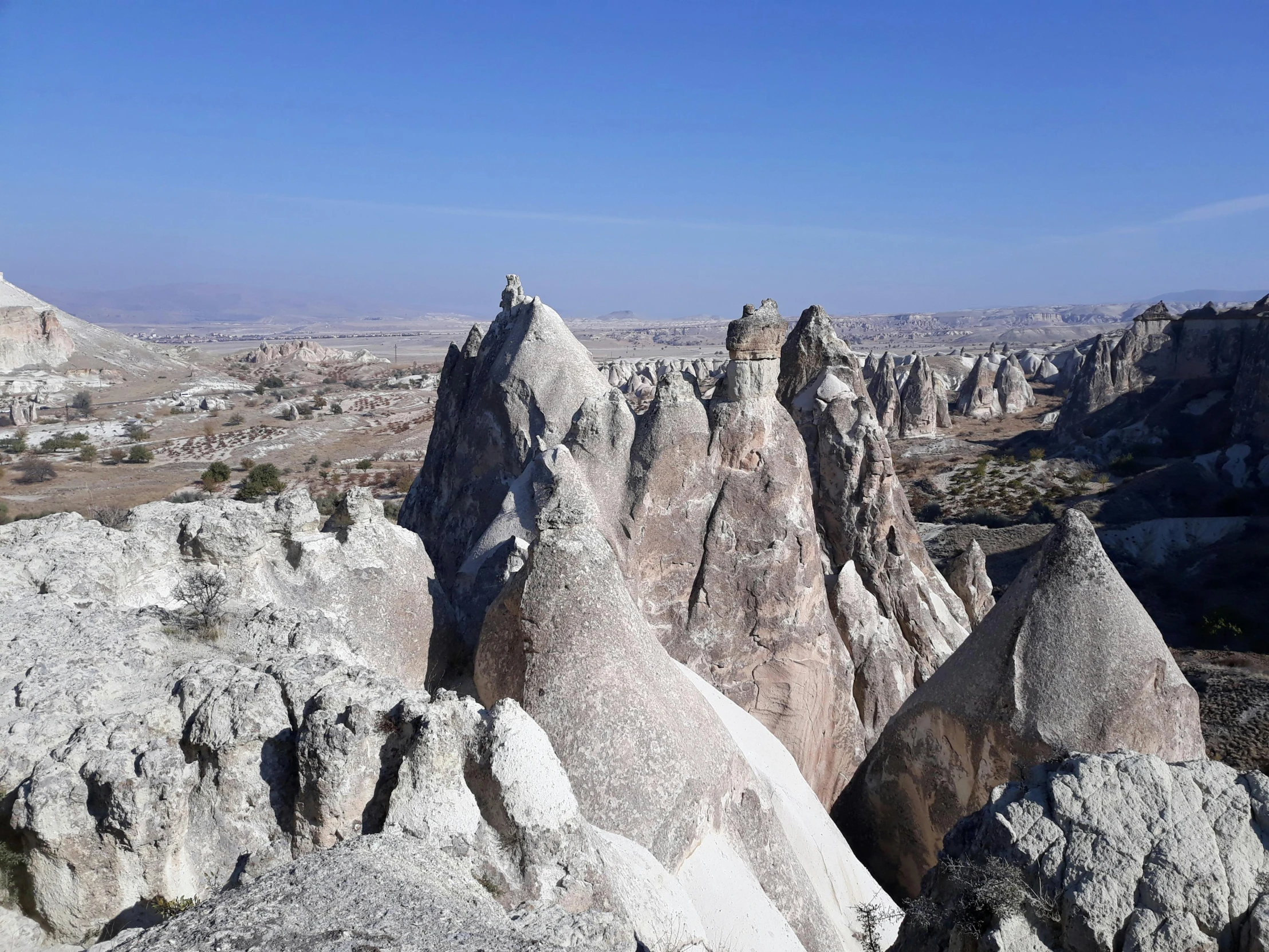 a person standing on top of a rock formation, black domes and spires, doruk erdem, as far as the eye can see, white