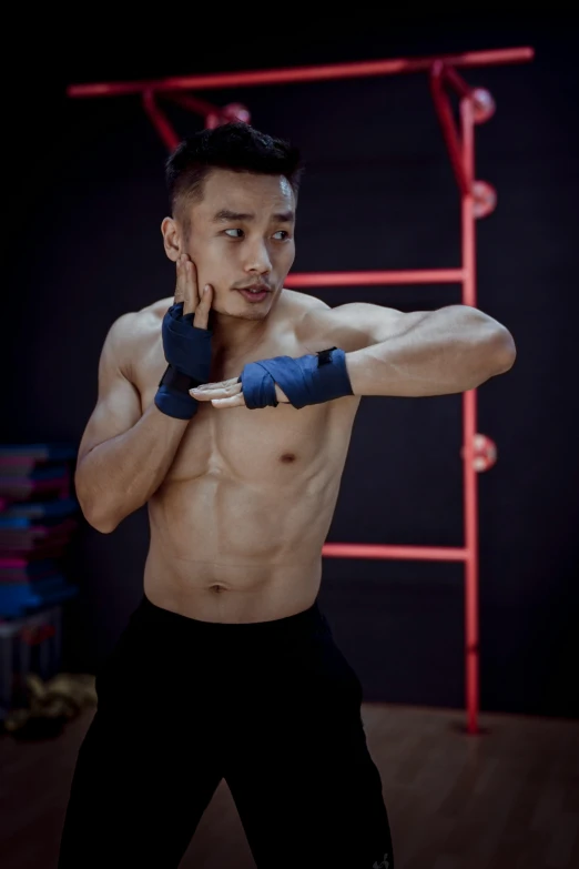 a shirtless man standing in front of a red ladder, inspired by Ma Quan, pexels contest winner, heroic muay thai stance pose, justin sun, pointed chin, thin young male