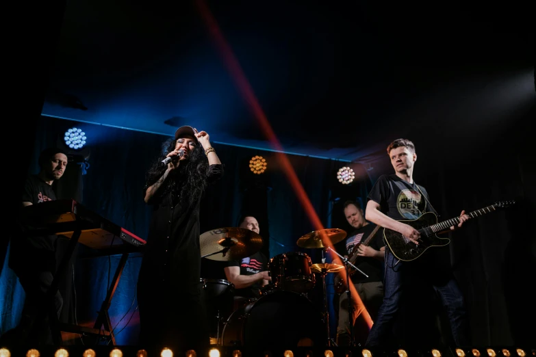a group of people standing on top of a stage, band playing, lit up in a dark room, gigachad jesus, promo image