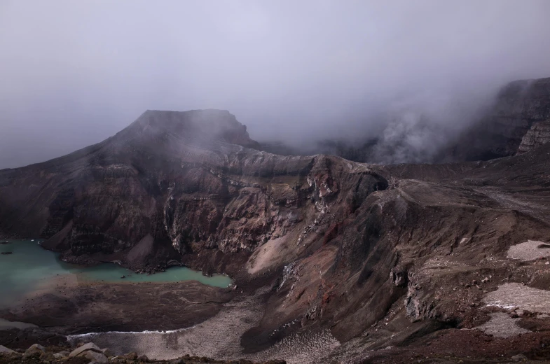 a group of people standing on top of a mountain, a photo, unsplash contest winner, hurufiyya, looking down at a massive crater, cold mist black background, green oozing pool pit, te pae