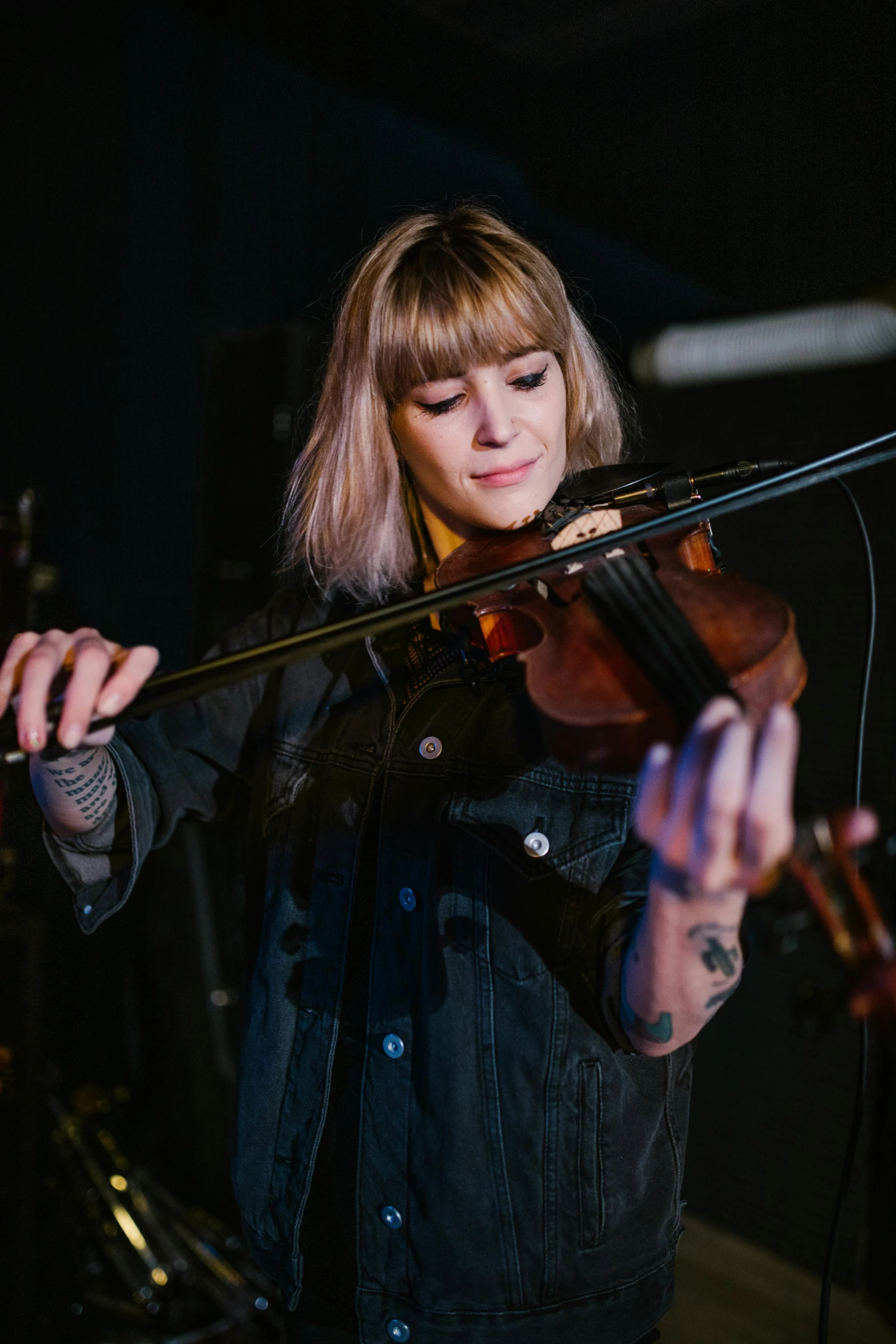 a woman playing a violin in front of a microphone, a portrait, unsplash, beth cavener, square, concert, tattooed