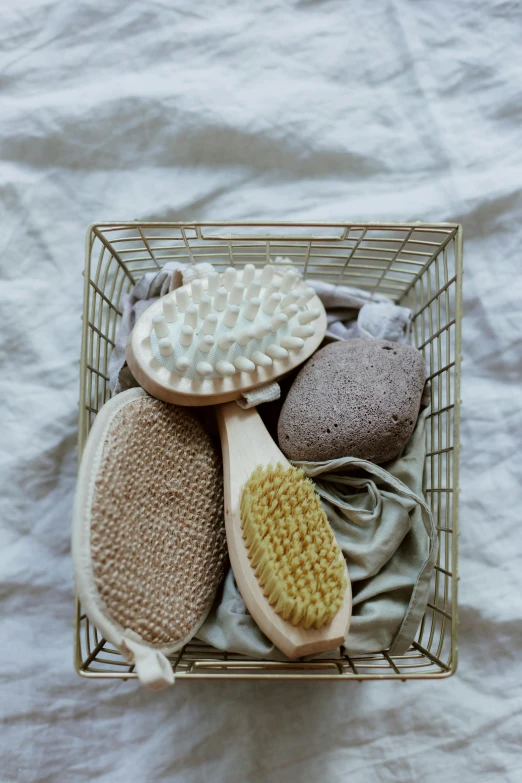 a basket filled with scrub brushes sitting on top of a bed, by Ivana Kobilca, unsplash, renaissance, pebbles, toys, creamy skin, boston