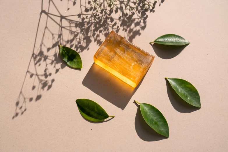 a soap bar sitting on top of a table next to green leaves, inspired by Joseph Beuys, trending on pexels, hurufiyya, glowing amber, organic crystals, solarised, made of glazed