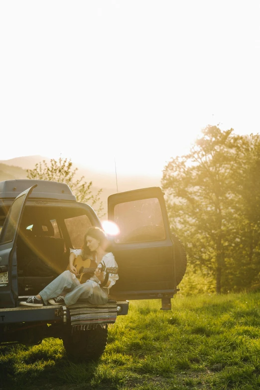 a dog sitting in the back of a pickup truck, a picture, pexels contest winner, romanticism, women playing guitar, at sunrise in springtime, campsites, outside on the ground