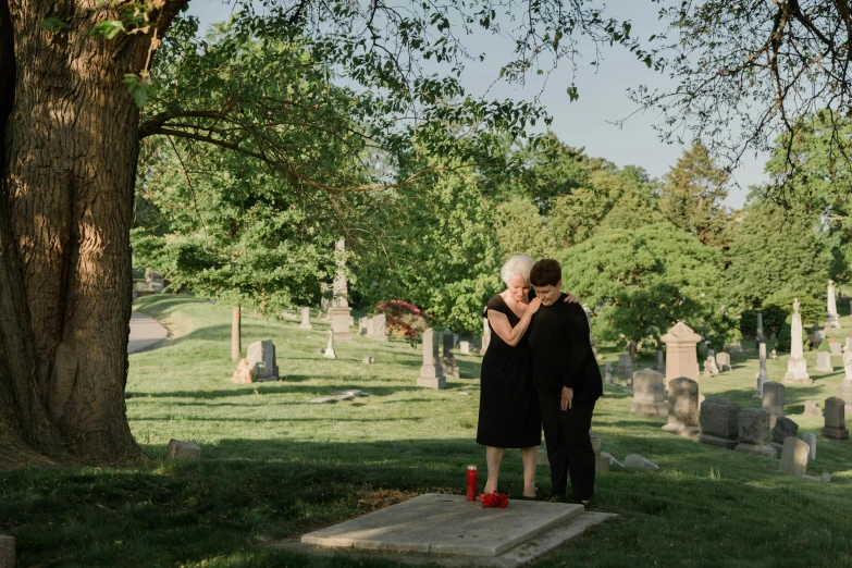 a woman standing next to a man in a cemetery, by Alison Geissler, unsplash, lesbian embrace, ignant, crewdson, beth harmon