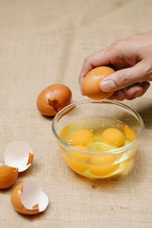 a person is peeling an egg in a bowl, an illustration of, trending on pexels, raw egg yolks, transparent, long, highly detailded'