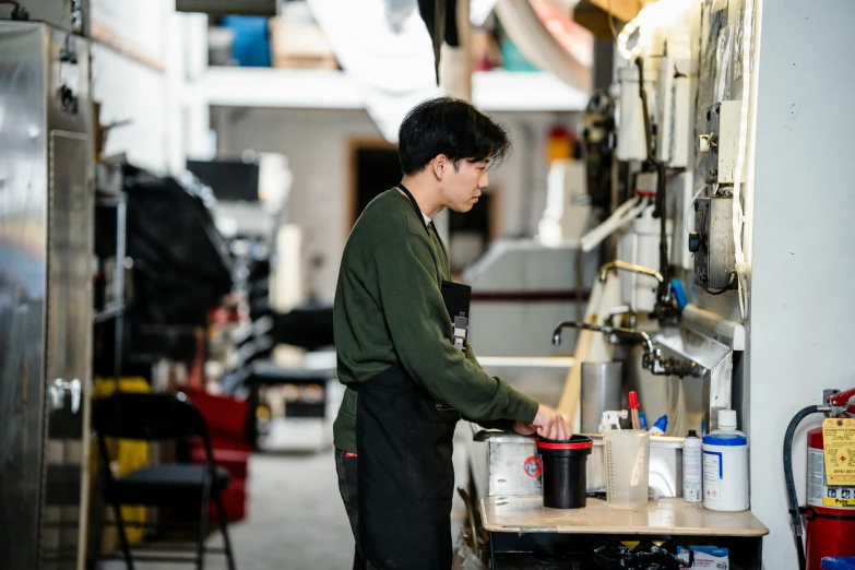 a man that is standing in a kitchen, machineparts, darren quach, white wall coloured workshop, working hard