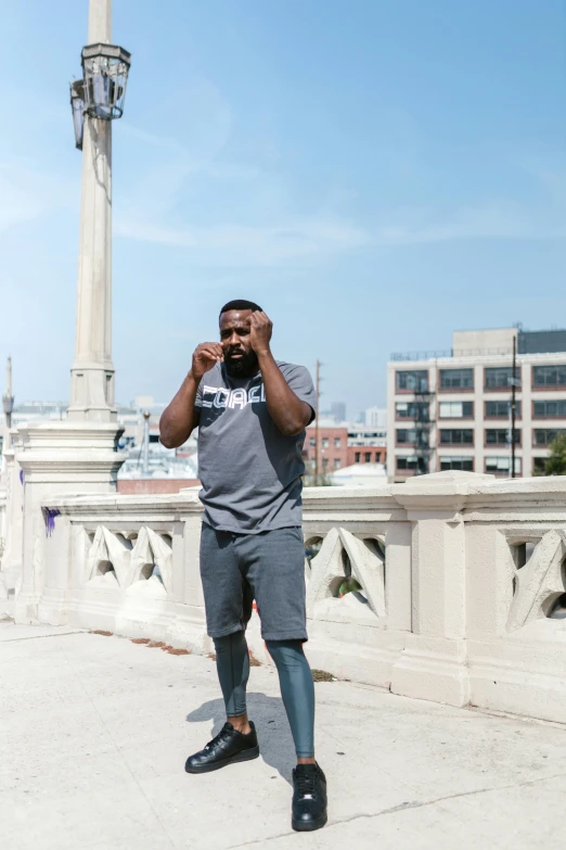 a man standing on a bridge talking on a cell phone, inspired by Paul Georges, happening, wearing a muscle tee shirt, bruh moment, standing on rooftop, gray men