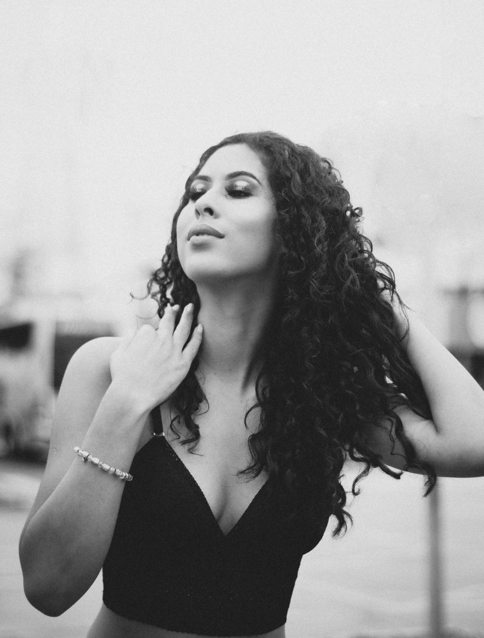 a black and white photo of a woman with curly hair, by Natasha Tan, arabesque, young middle eastern woman, square, smooth in _ the background, arm around her neck