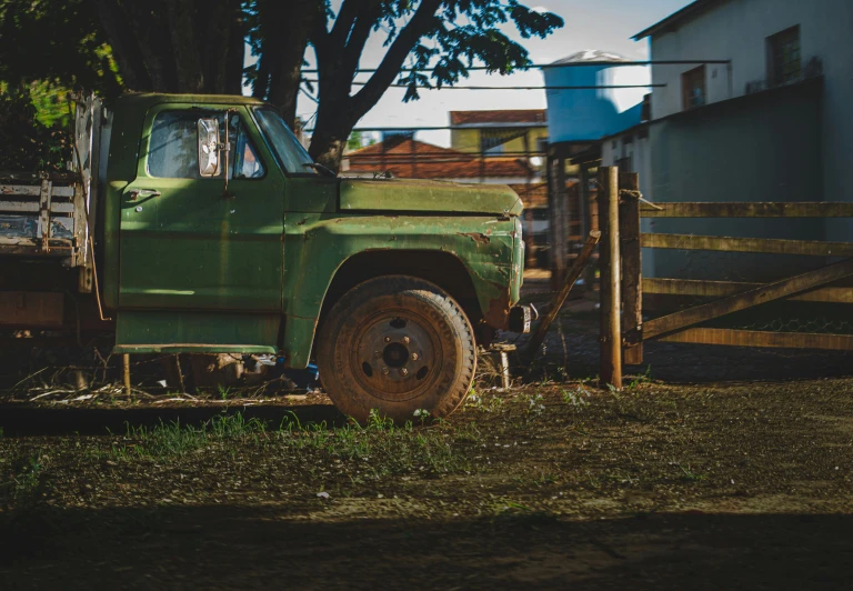 a green truck parked next to a wooden fence, by Elsa Bleda, pexels contest winner, square, ((rust)), ( ( ( ( kauai ) ) ) ), late afternoon light