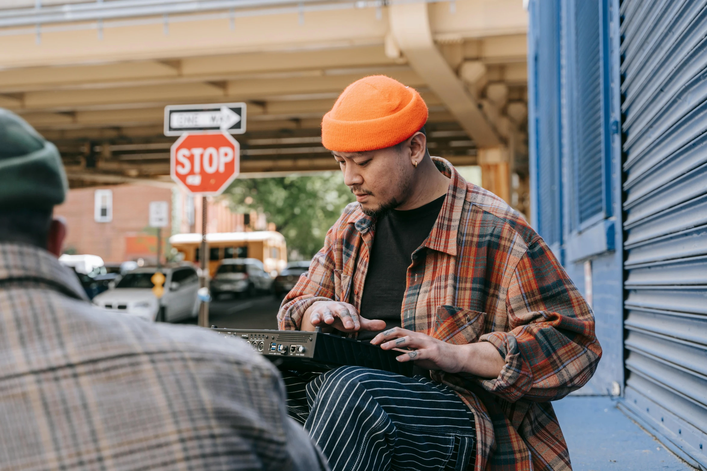 two men sitting next to each other on a sidewalk, trending on pexels, visual art, playing a korg ms-20 synthesizer, wearing a navy blue utility cap, with a laptop on his lap, zeen chin and farel dalrymple