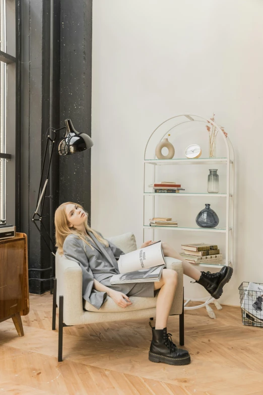 a woman sitting in a chair in a living room, inspired by Constantin Hansen, product display photograph, ekaterina, sleepy, shelves