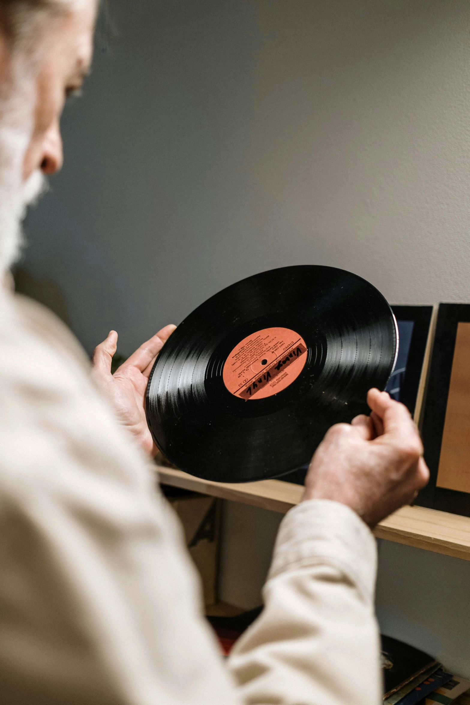 a man holding a record on a shelf, an album cover, by Everett Warner, pexels contest winner, old man, music being played, high resolution product photo, framed in image