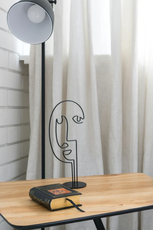 a table with a lamp and a book on it, an abstract sculpture, inspired by Diego Giacometti, unsplash, face line drawing, detailed product image, portrait of small, face accessories