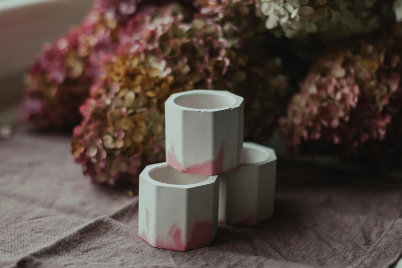 a couple of cups sitting on top of a table, a marble sculpture, inspired by Rachel Whiteread, featured on instagram, petal pink gradient scheme, close-up product photo, hexagonal, with soft bushes