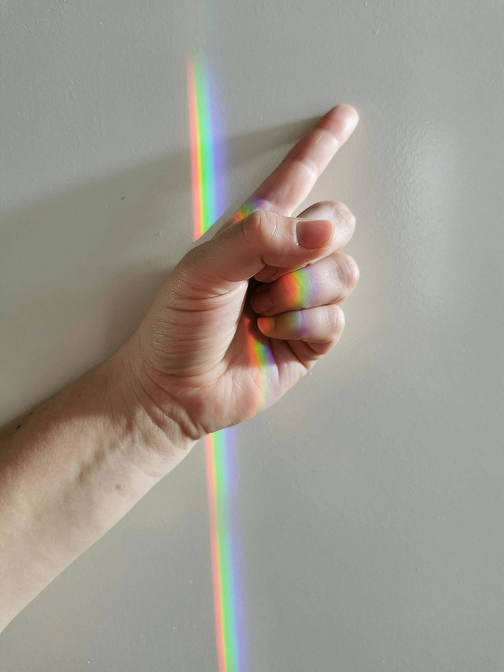 a hand making a peace sign with a rainbow in the background, a hologram, inspired by Gabriel Dawe, pexels, on a gray background, directional sunlight skewed shot, light entering through a blind, rinko kawauchi