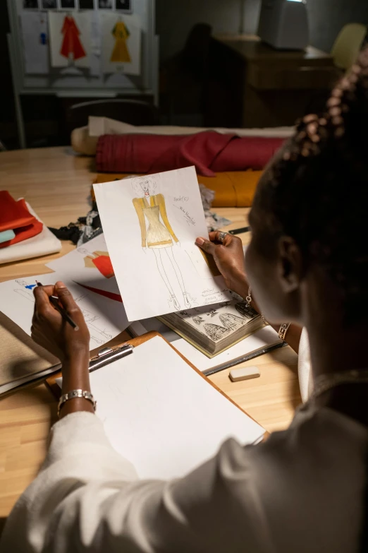 a woman sitting at a table writing on a piece of paper, a drawing, inspired by Afewerk Tekle, haute couture, promotional image, thumbnail, inspect in inventory image