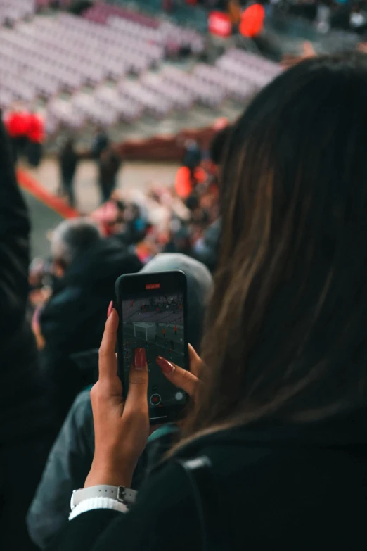 a woman taking a picture of a crowd of people, by Niko Henrichon, trending on unsplash, standing in a stadium, spying discretly, integrating with technology, award winning image