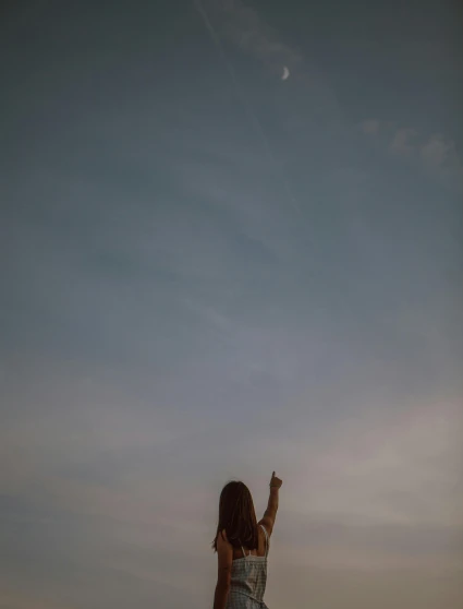 a woman flying a kite on top of a sandy beach, a picture, by Attila Meszlenyi, holding the moon upon a stick, jovana rikalo, raised hand, slightly pixelated