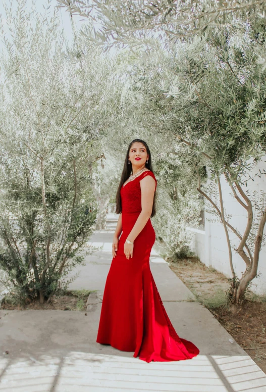a woman in a red dress standing in front of a tree, wearing a formal dress, cindy avelino, square, low quality photo