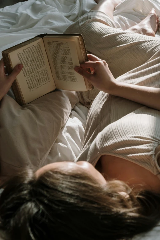 a woman laying in bed reading a book, pexels contest winner, renaissance, top-down shot, open belly, gif, soft backlighting