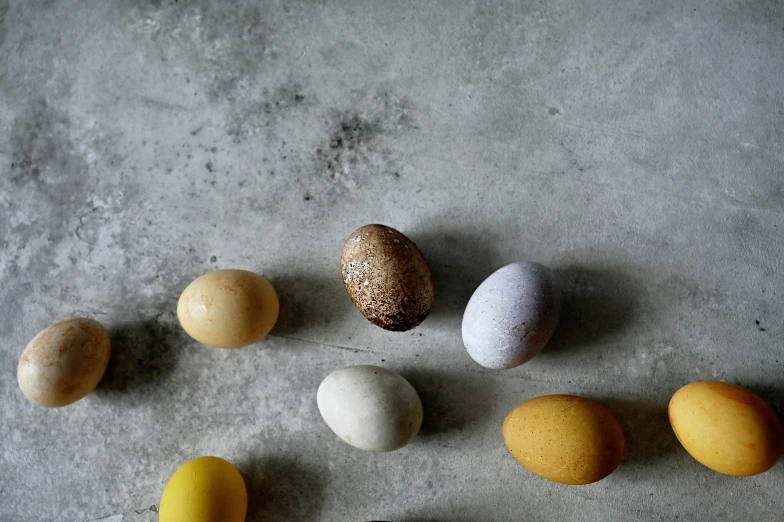 a bunch of eggs sitting on top of a table, concrete, multicoloured, small, handcrafted