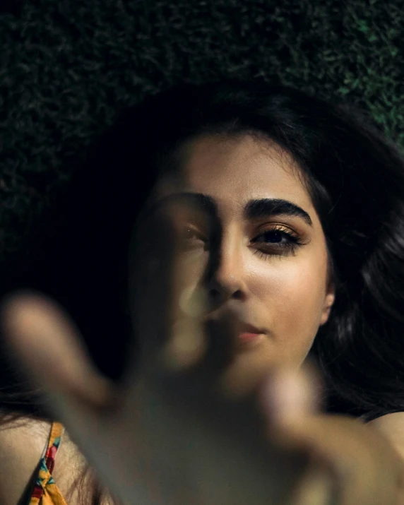 a woman making a stop sign with her hand, an album cover, by irakli nadar, trending on pexels, close - up face portrait from up, maya ali mage, laying down, in love selfie