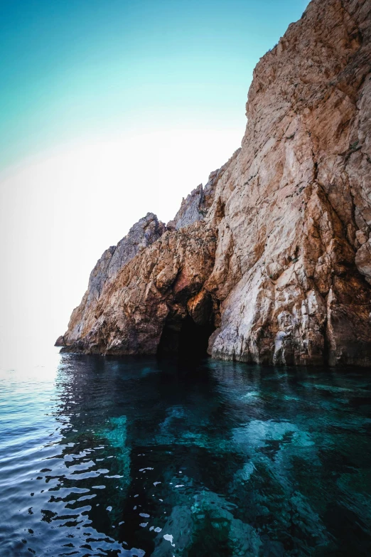 a cave in the middle of a body of water, steep cliffs, piroca, less detailing, instagram picture