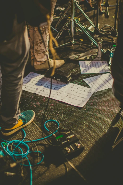 a group of people standing next to each other on a stage, an album cover, by Matt Cavotta, pexels contest winner, thick cables on ground, sheet music, stoner rock concert, music being played