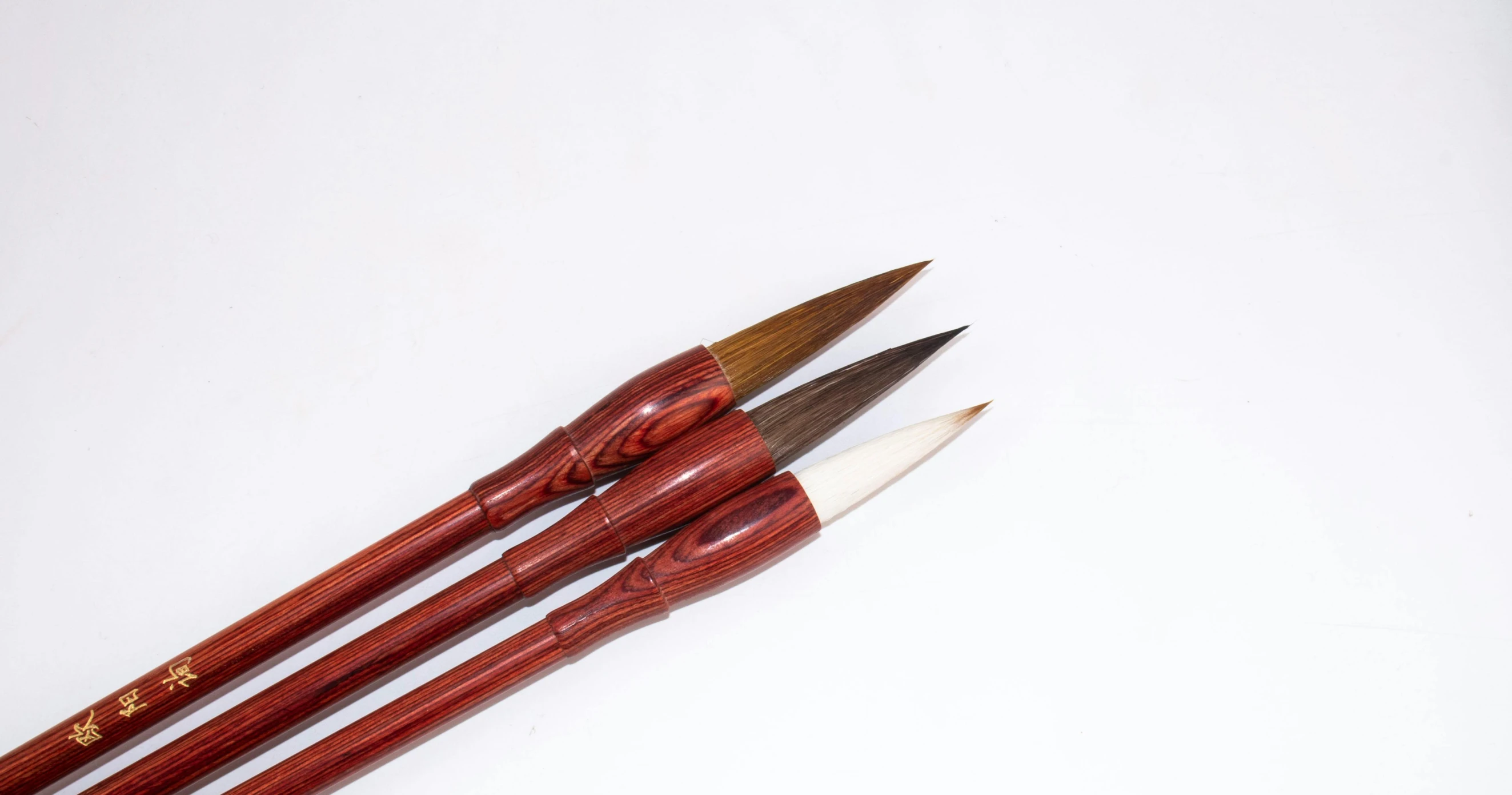 three brushes sitting next to each other on a white surface, by Liang Kai, dau-al-set, fine pen, arrow shaped, brown, 6 0's