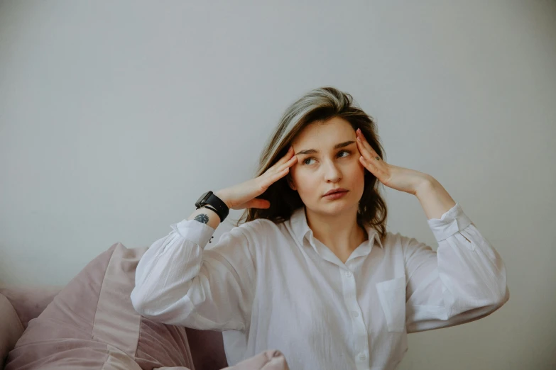 a woman in a white shirt sitting on a bed, trending on pexels, showing forehead, sitting on a couch, tinnitus, various posed