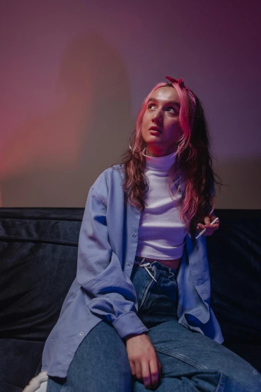 a woman sitting on top of a black couch, a portrait, trending on pexels, realism, pink and blue lighting, portrait sophie mudd, woman in streetwear, saoirse ronan