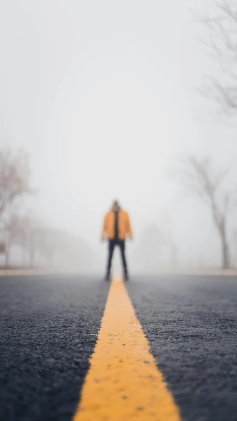 a person standing in the middle of a road on a foggy day, light orange mist, sad man, scary, foggy photo 8 k