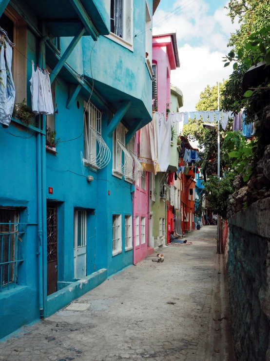 a narrow alley with clothes hanging out to dry, an album cover, by Elsa Bleda, fauvism, built on a steep hill, south beach colors, blueish, colorul