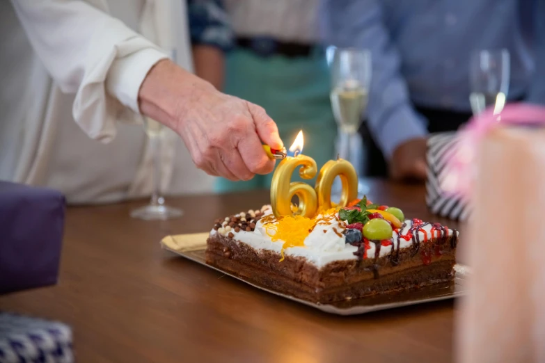 a person lighting a candle on a birthday cake, by Daniel Gelon, pexels contest winner, hyperrealism, she is about 6 0 years old, golden number, triple six, snacks